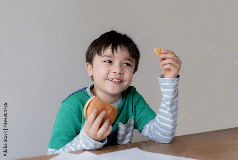Healthy young boy eating burger. A child holding cheeseburger and