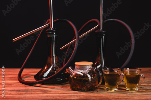 Teapot near hookahs on wooden table isolated on black. © LIGHTFIELD STUDIOS