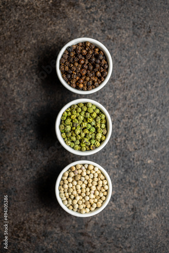 Three different types of pepper spice. Green, white and black peppercorn in bowls.