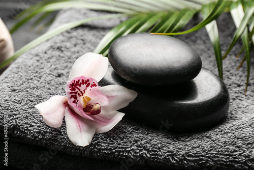 Spa stones with orchid flower on bathing towel  closeup