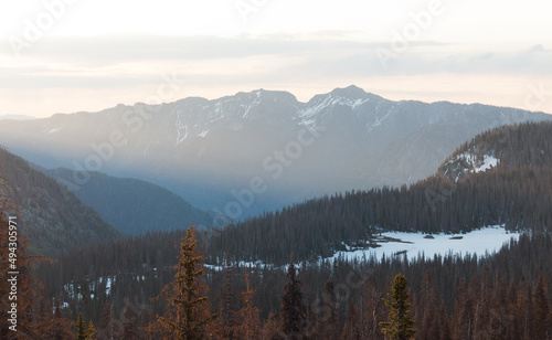 Multi-layered sunrise mountain landscape with sun rays and snow 