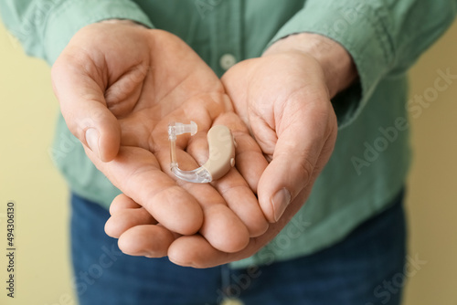 Man with hearing aid on color background, closeup