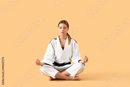 Female karate instructor meditating on color background photo