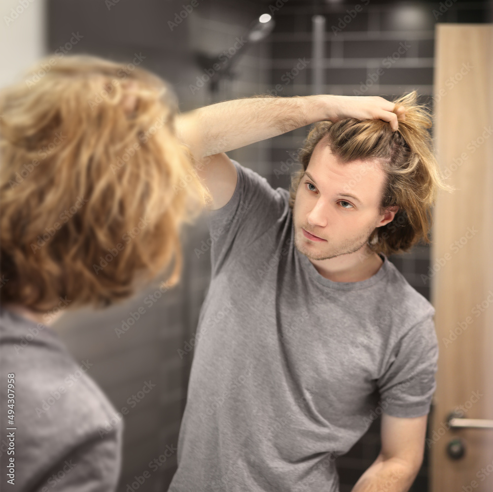 young man looking in the mirror,combing his hair,looking at problems on face. young man looking in the mirror,combing his hair,looking at problems on face.