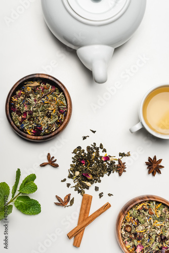 Top view of dry tea in bowls  teapot and spices on white background.