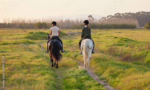 A horse loves freedom. Shot of two unrecognizable women riding their horses outside on a field.