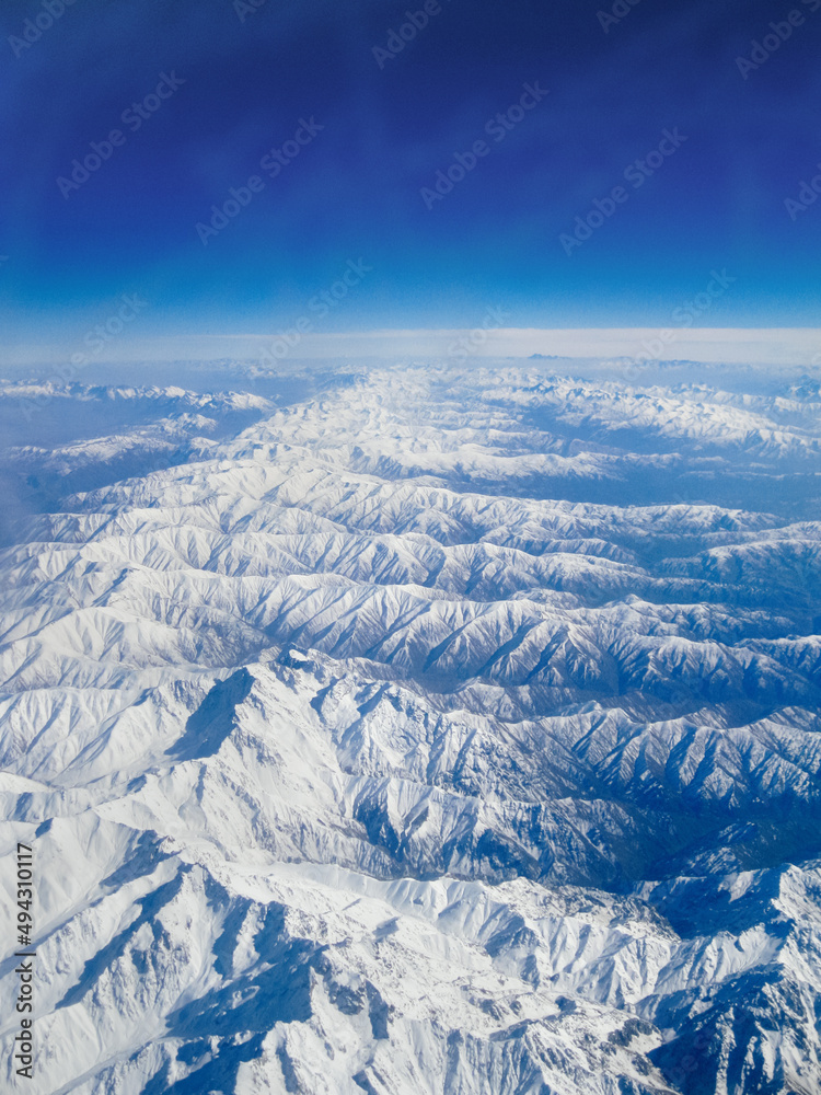 Fototapeta premium Landscape of the Alps. View from the window of the plane on the snowy mountains. Top view.