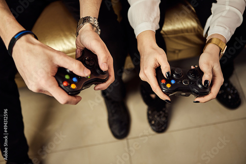 playful couple, Gamers enjoying Playing Video Games indoors sitting on the sofa, holding Console Gamepad in hands. Resting At Home, have a great Weekend. X-BOX