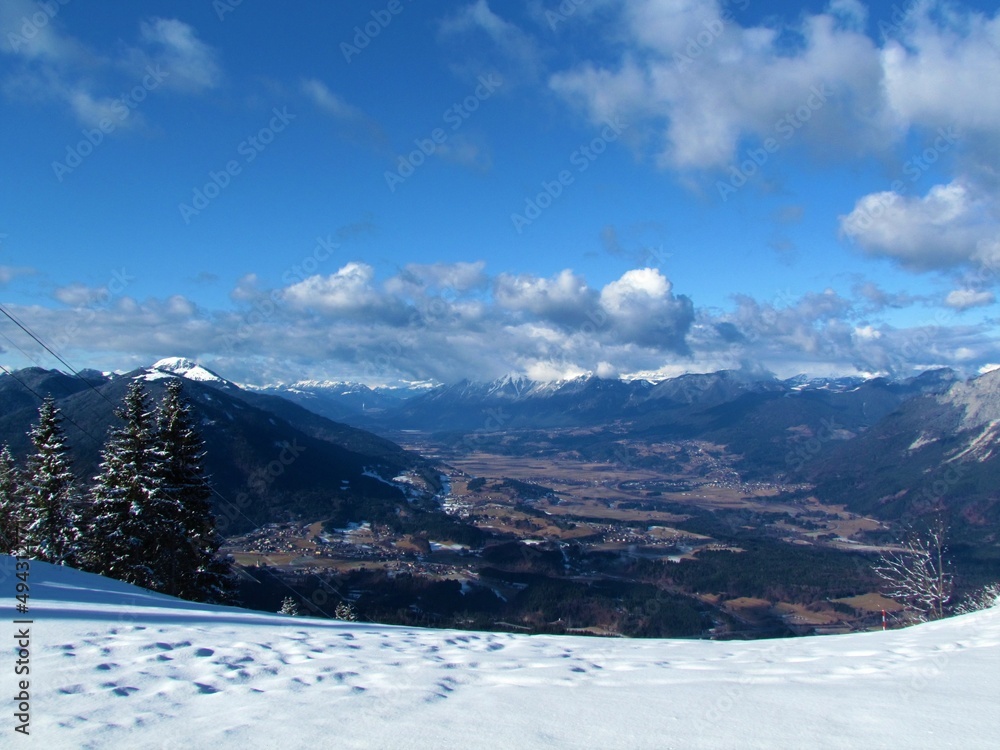 Obraz premium Scenic view of Gailtal in Carinthia or Karnten in Austria covered in farmland and surrounded by high mountains of Gailtal Alps in winter from Tromeja or Mt. Ofen