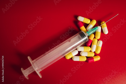 medical pills with srynge on red background photo