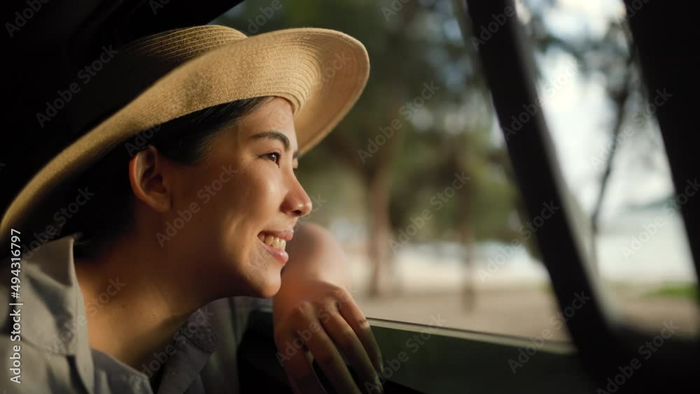 A young beautiful asian woman travel to the sea by car on a bright day. With beautiful blue sky. Vacation holiday weekend after hard work. Sticking her head outta the windshield