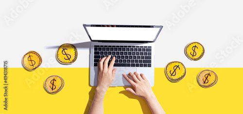 Foto Person using a laptop computer with coins - earn online - work from home themes