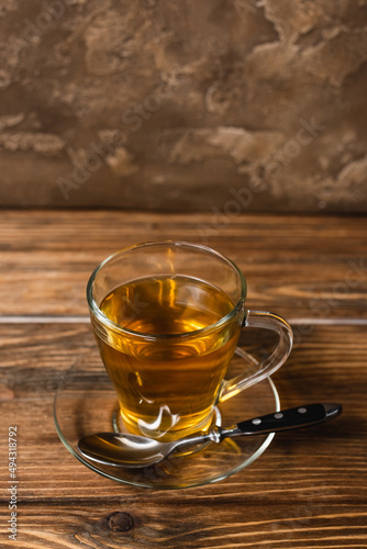 High angle view of cup of tea on saucer on wooden surface on textured stone background.