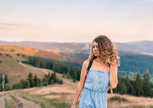Curly young woman with a bunch of chamomiles enjoying the view in the top of mountain on a hot summer day. young pretty woman closeup. Lifestyle concept