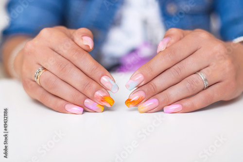 Beautiful female hands with multicoloured manicure nails, pink, blue and orange gel polish
