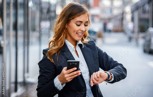 Always on time. Businesswoman looking at her watch while waiting a money transfer on the way to office. Business, lifestyle concept photo