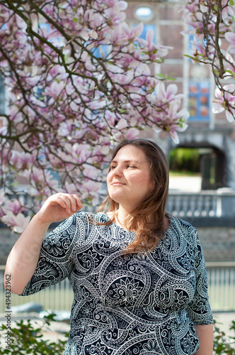 Portrait of a beautiful plump caucasian confident woman in magnolia flowers photo