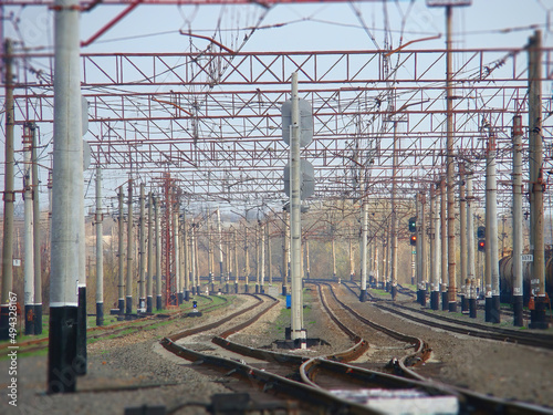 The interlacing of the rails at the station surrounded by wires and poles. Industrial landscape background