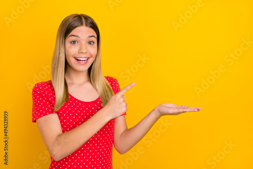 Photo of cheerful excited person direct finger arm palm demonstrate empty space isolated on yellow color background