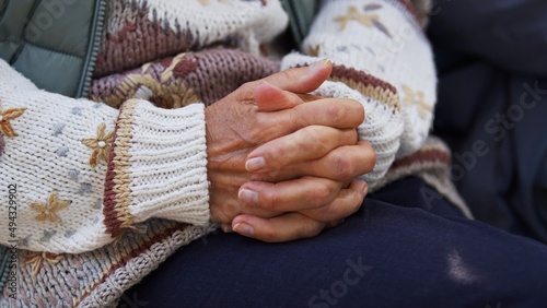 Senior Caucasian lady interlocks her fingers knitted clothes close up selective focus . High quality photo