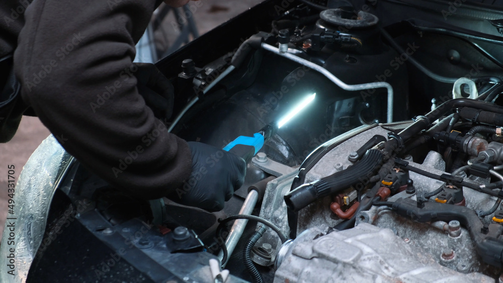 Replacing the engine timing belt in an automobile. Auto mechanic in a car repair center. Replacement of automobile oil and filter Replacing the engine timing belt in an automobile. Auto mechanic in a car repair center. Replacement of automobile oil and filter