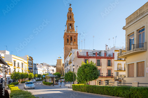 The main street through Carmona, Spain, with the Puerta de Sevilla Alcazar and Church of San Pedro tower in view in the distance.