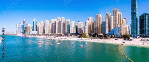 New modern skyscrapers tower viewed from beach against clear blue sky on sunny day, Modern luxury skyscrapers with beach