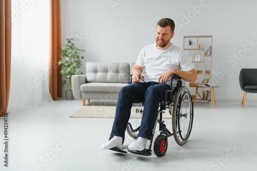 Young sad man in a wheelchair at home.