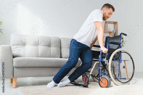 disabled man at home tries to get to his feet in a wheelchair. The concept of rehabilitation after injuries and car accidents.
