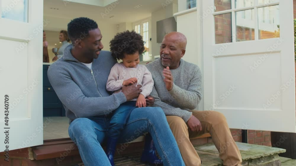 Grandfather with father and son sitting on step at home giving each other high fives - shot in slow motion Grandfather with father and son sitting on step at home giving each other high fives - shot in slow motion