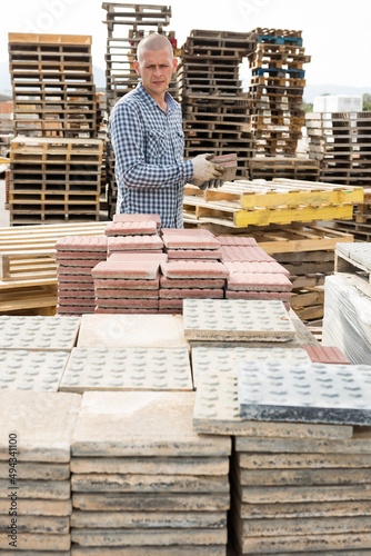 Concentrated man worker controlling quantity of tiles at hardware store warehouse