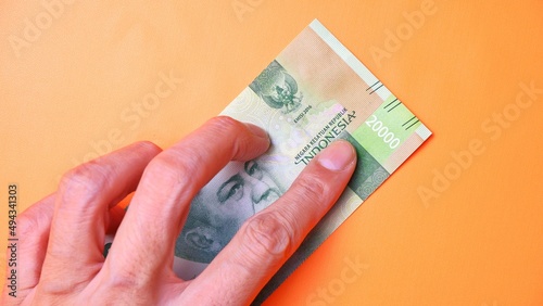 Indonesian Rupiah the official currency of Indonesia. Man's hand is making a payment. Male hand showing Indonesian Rupiah note. Business Investment Economy and Finance concept Uang 20000 20.000 Rupiah