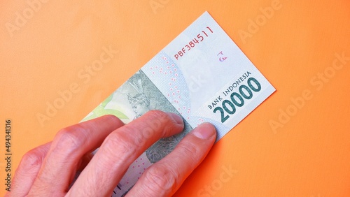 Indonesian Rupiah the official currency of Indonesia. Man's hand is making a payment. Male hand showing Indonesian Rupiah note. Business Investment Economy and Finance concept Uang 20000 20.000 Rupiah