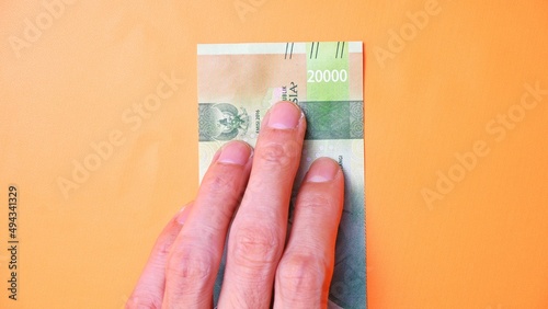 Indonesian Rupiah the official currency of Indonesia. Man's hand is making a payment. Male hand showing Indonesian Rupiah note. Business Investment Economy and Finance concept Uang 20000 20.000 Rupiah