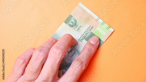 Indonesian Rupiah the official currency of Indonesia. Man's hand is making a payment. Male hand showing Indonesian Rupiah note. Business Investment Economy and Finance concept Uang 20000 20.000 Rupiah
