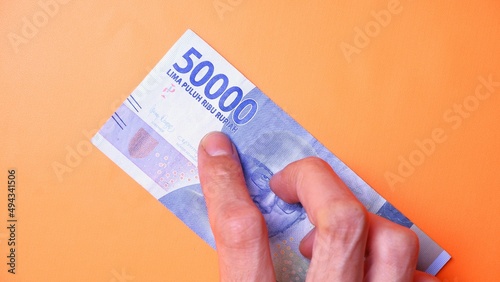 Indonesian Rupiah the official currency of Indonesia. Man's hand is making a payment. Male hand showing Indonesian Rupiah note. Business Investment Economy and Finance concept Uang 50000 50.000 Rupiah