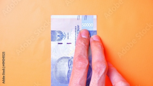 Indonesian Rupiah the official currency of Indonesia. Man's hand is making a payment. Male hand showing Indonesian Rupiah note. Business Investment Economy and Finance concept Uang 50000 50.000 Rupiah