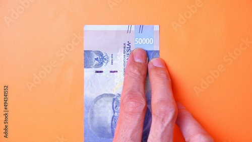Indonesian Rupiah the official currency of Indonesia. Man's hand is making a payment. Male hand showing Indonesian Rupiah note. Business Investment Economy and Finance concept Uang 50000 50.000 Rupiah