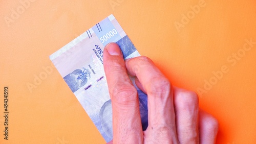 Indonesian Rupiah the official currency of Indonesia. Man's hand is making a payment. Male hand showing Indonesian Rupiah note. Business Investment Economy and Finance concept Uang 50000 50.000 Rupiah