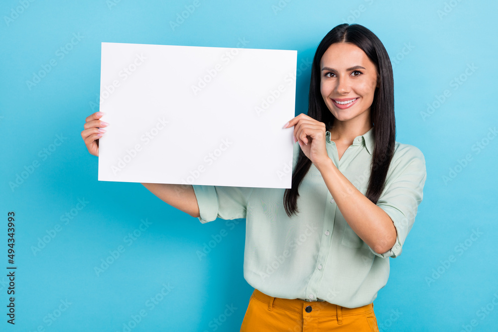 Photo of young pretty cheerful woman hold paper poster news advertise isolated over blue color background Photo of young pretty cheerful woman hold paper poster news advertise isolated over blue color background