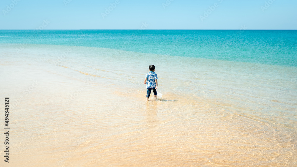 Happy little boy playing on the sand with sea, summer beach.