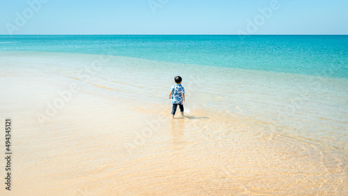 Happy little boy playing on the sand with sea, summer beach.