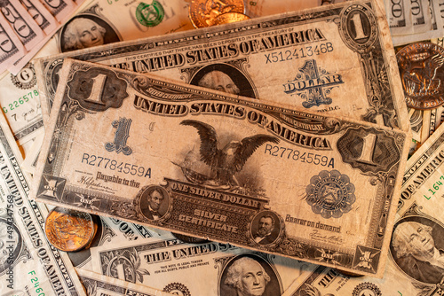 Silver certificate one Dollar banknote on top of Dollar coins and new USD banknotes issued by Federal Reserve bank
