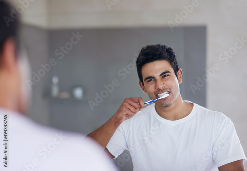 He brushes twice daily for optimal oral health. Shot of a young man brushing his teeth at home.