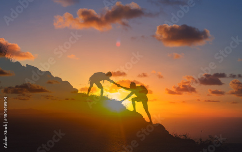 Helping a friend giving support and a helping hand climbing a mountain, people working together as a team. 