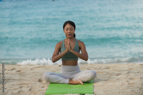 yoga in the beach. woman practicing yoga alone in the beach. Wearing sport bar. She is barefoot. She is against sea an d sand beach.