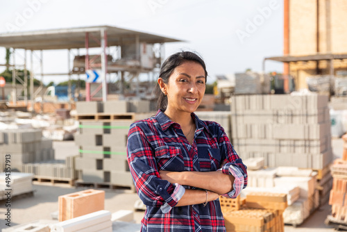 Obraz na plátně Portrait of positive hispanic female supervisor standing in warehouse of hardwar