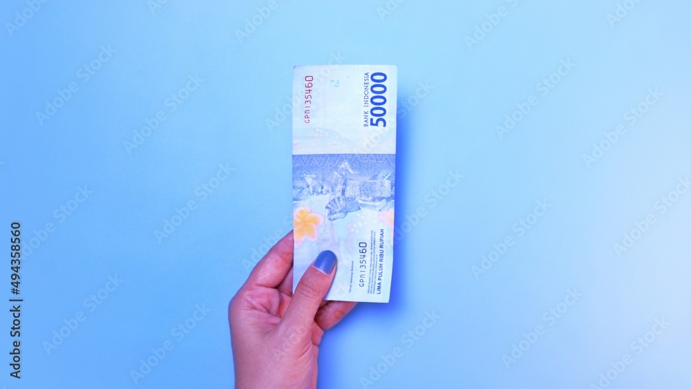 Indonesian Rupiah the official currency of Indonesia. woman's hand is making a payment. Female hand showing Indonesian Rupiah note. Business Investment Economy and Finance concept. Uang 50000 Rupiah Indonesian Rupiah the official currency of Indonesia. woman's hand is making a payment. Female hand showing Indonesian Rupiah note. Business Investment Economy and Finance concept. Uang 50000 Rupiah