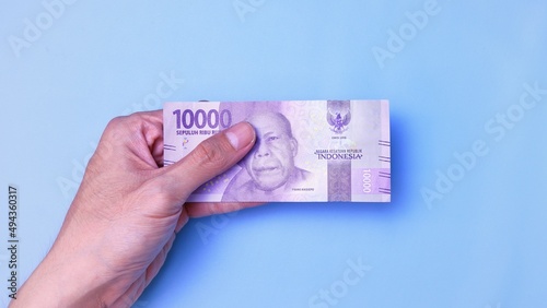 Indonesian Rupiah the official currency of Indonesia. Man's hand is making a payment. Business Loan Income Money Investment Economy and Finance Concept Uang 10000 10.000 Rupiah. Prosperity Concept.