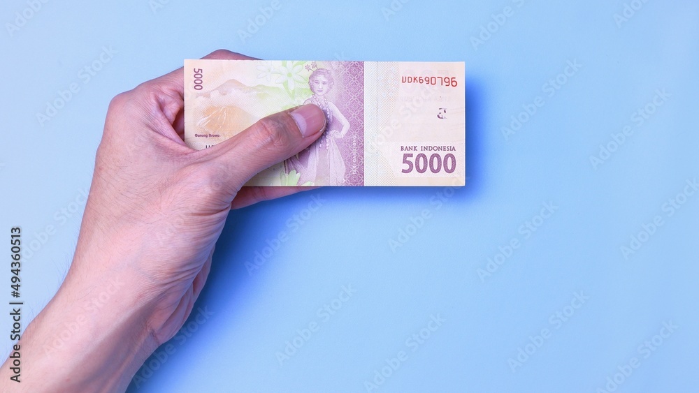 Indonesian Rupiah the official currency of Indonesia. Man's hand is making a payment. Business Loan Income Money Investment Economy and Finance Concept Uang 5000 5.000 Rupiah. Prosperity Concept. Indonesian Rupiah the official currency of Indonesia. Man's hand is making a payment. Business Loan Income Money Investment Economy and Finance Concept Uang 5000 5.000 Rupiah. Prosperity Concept.